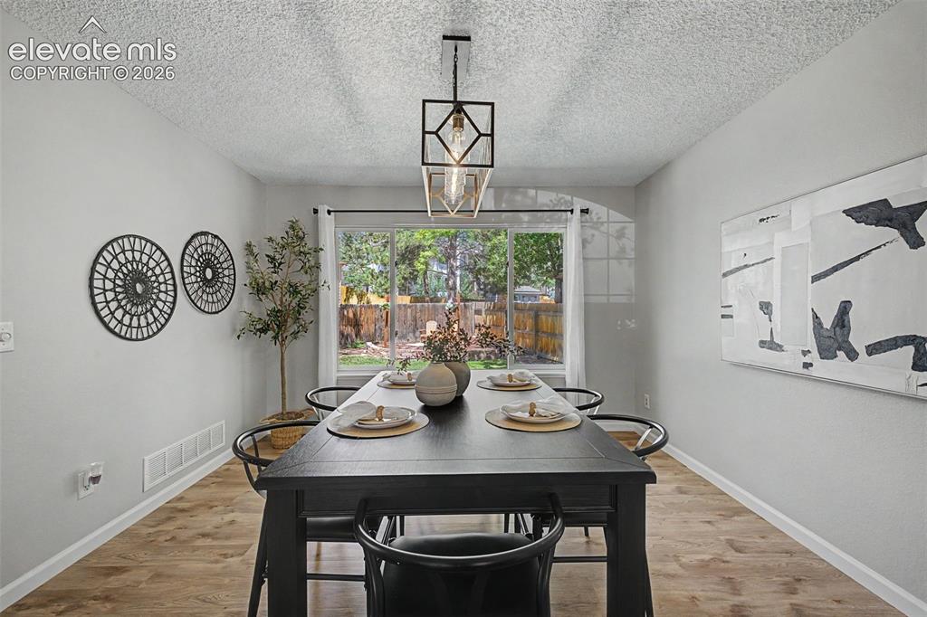 Image 14 of 49: Dining area with wood-finish flooring, light gray walls, and a contemporary