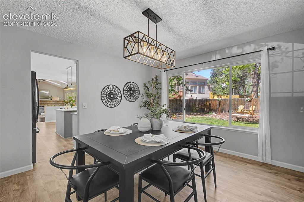 Image 15 of 49: Dining area with wood-finish flooring, a contemporary geometric chandelier,