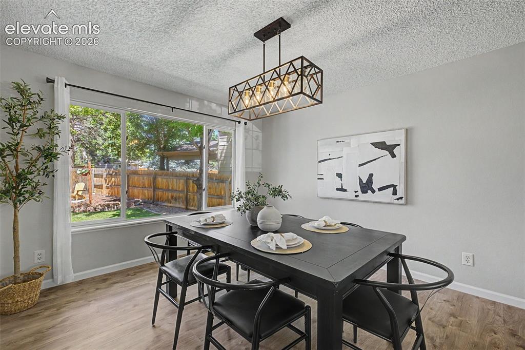 Image 17 of 49: Dining area featuring wood-finish flooring, a contemporary linear chandelie