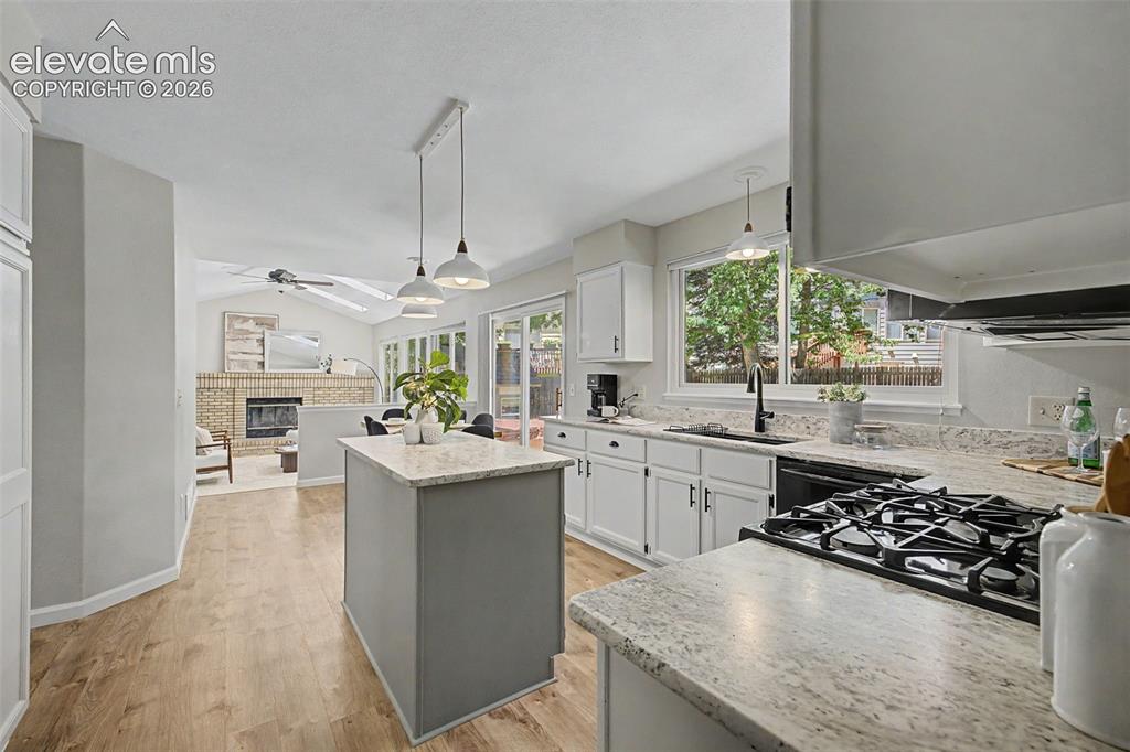 Image 18 of 49: Kitchen featuring granite countertops, a gas range, wood-finish flooring, a
