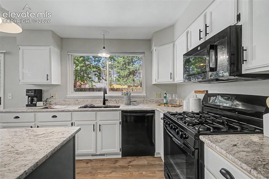 Image 19 of 49: Contemporary kitchen featuring white cabinetry, black hardware, speckled co