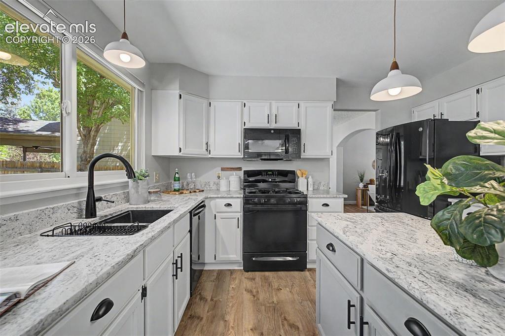Image 22 of 49: Kitchen featuring white cabinetry, light-toned countertops, black appliance