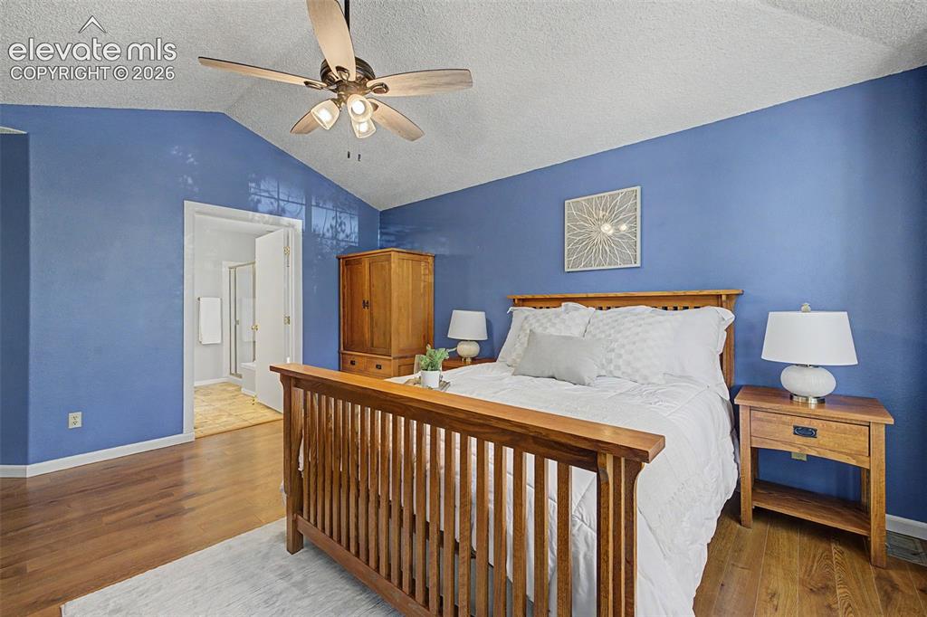 Image 32 of 49: Spacious room featuring vaulted ceilings and warm wood-finish flooring