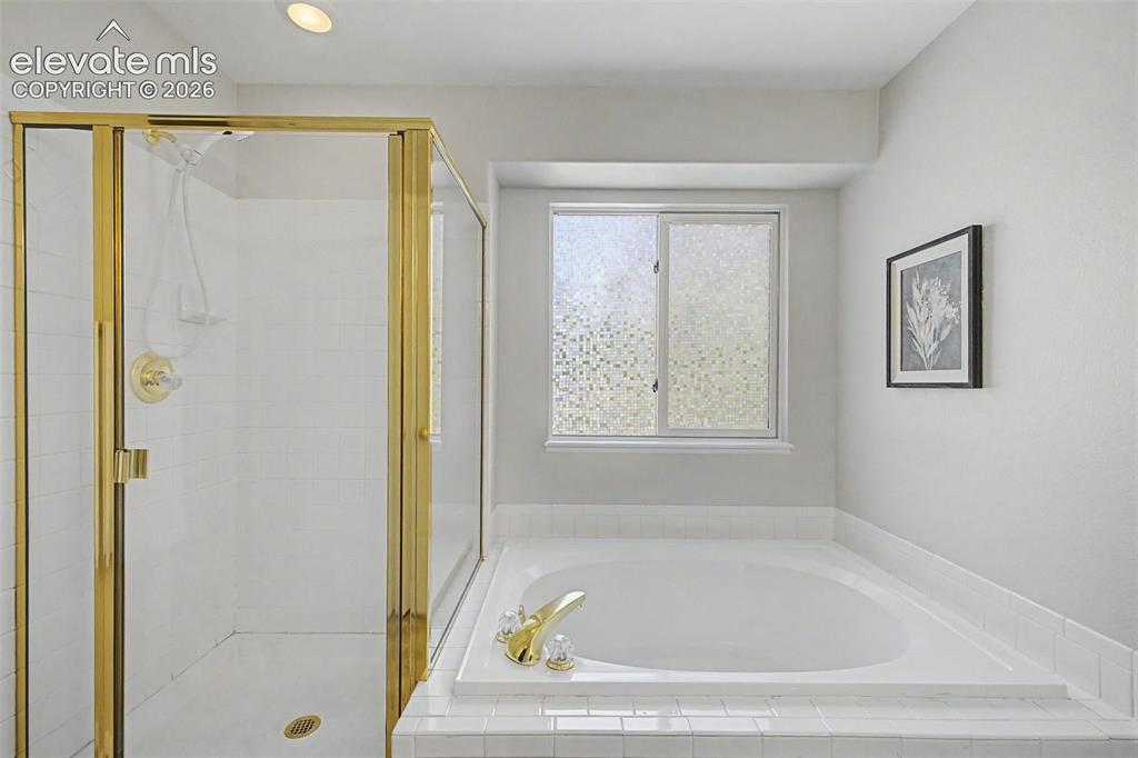 Image 35 of 49: Bathroom featuring a built-in soaking tub with white tile surround, a glass