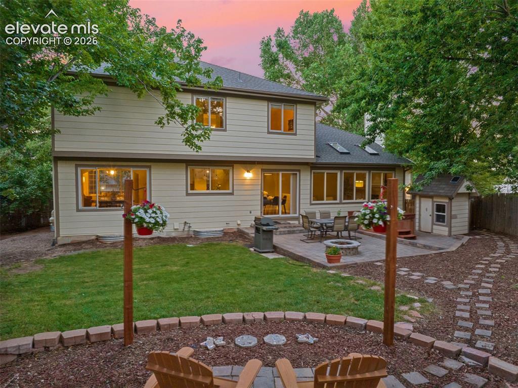 Image 4 of 49: Expansive backyard featuring a paver patio, integrated fire pit, and a sepa