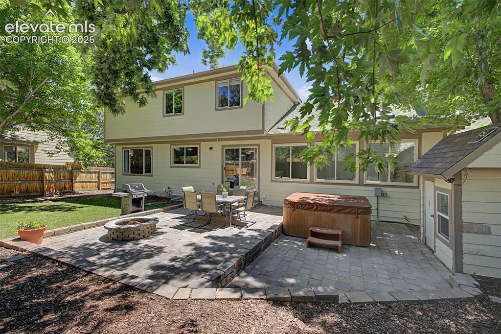 Image 44 of 49: Spacious backyard featuring a multi-level paver patio, integrated fire pit,