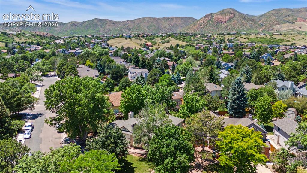 Image 7 of 49: Expansive residential area featuring mature tree cover and mountain backdro