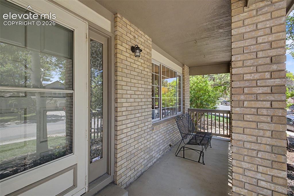 Image 8 of 49: Inviting front porch featuring a brick exterior, concrete flooring, and a d