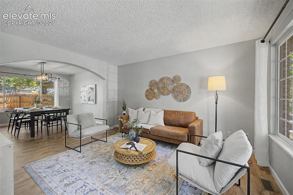 Image 9 of 49: Open-concept living area featuring wood-finish flooring, a decorative arche