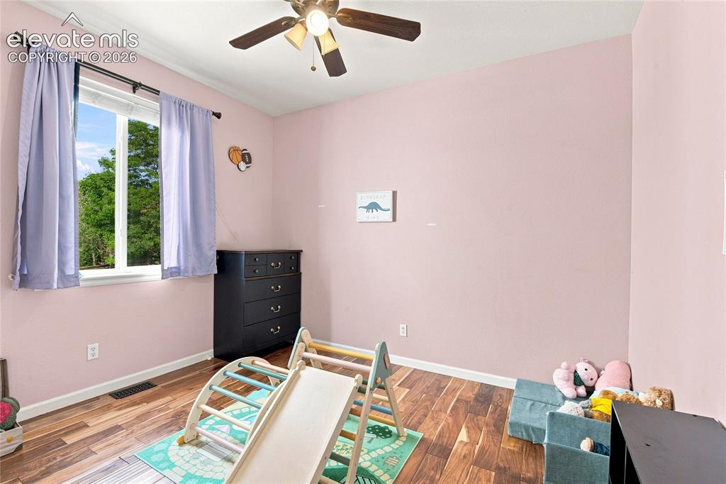 Image 12 of 18: Wood-finish flooring, ceiling fan, and a window with exterior visibility