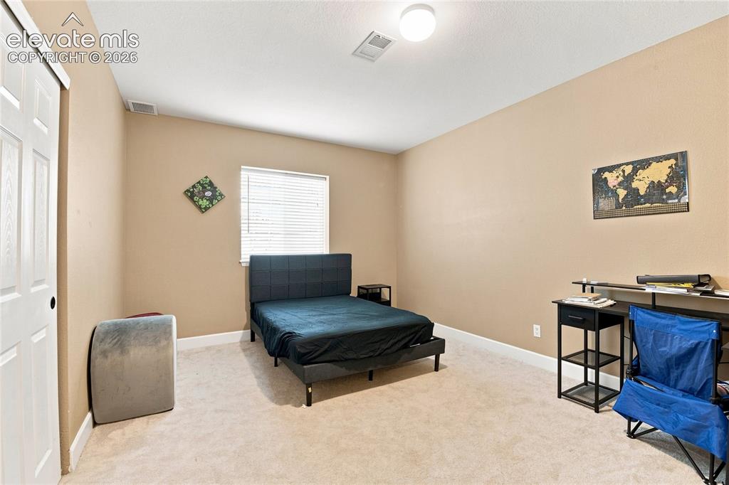 Image 15 of 18: Carpeted room with a window featuring blinds, a built-in light fixture, and