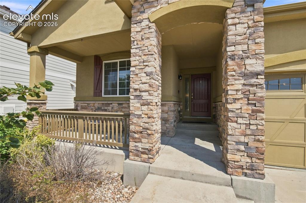 Image 2 of 18: Stone veneer accents, covered front porch, wood-paneled garage door, decora