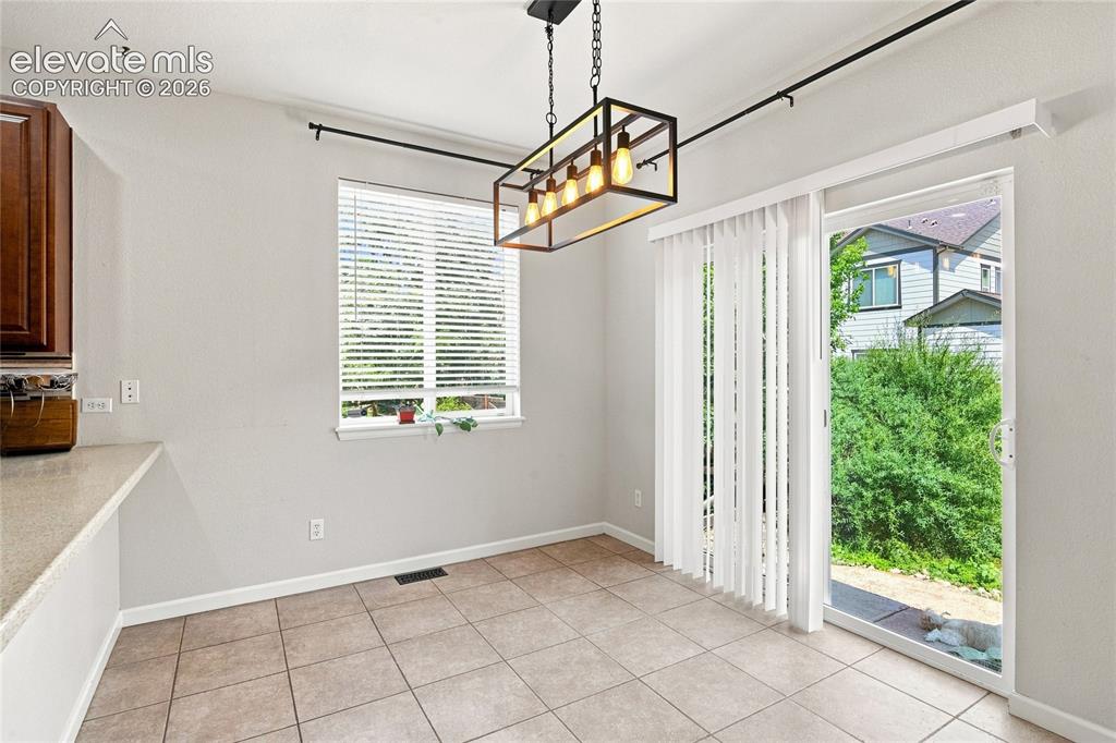 Image 6 of 18: Tile flooring, modern linear chandelier, sliding glass door, window with bl
