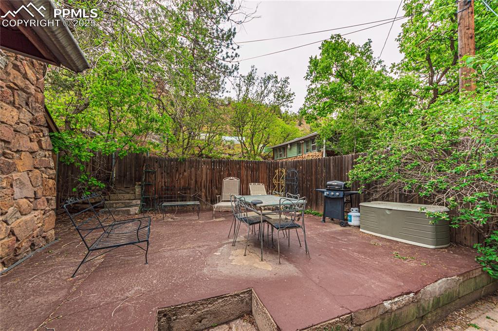 Image 17 of 23: Fenced backyard with a patio area, a grill, and outdoor dining area