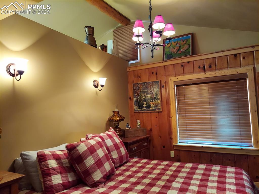 Image 2 of 23: Bedroom with a chandelier and wood walls