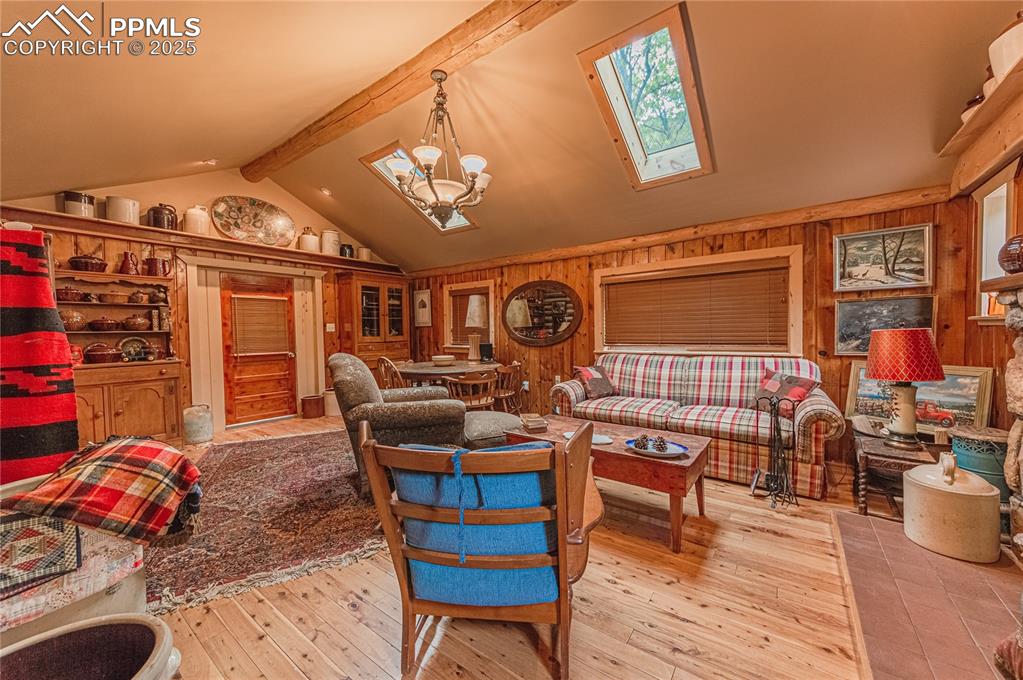 Image 5 of 23: Living area featuring beamed ceiling, light wood-style flooring, a chandeli