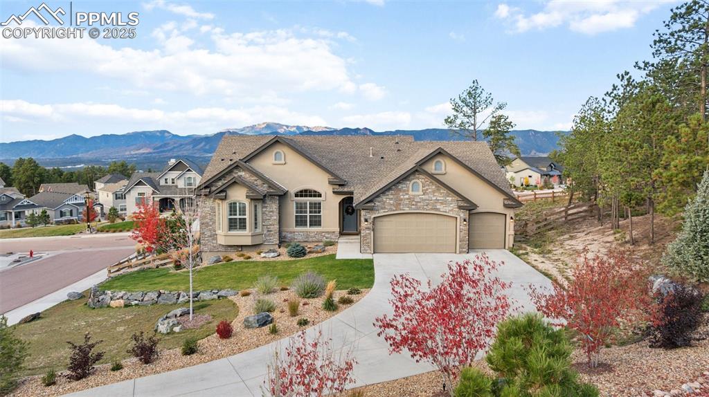 Caption: French country home featuring a mountain view, stucco siding, concrete driveway, a garage, and stone
