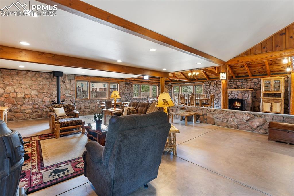 Image 9 of 48: The sprawling great room features a vaulted ceiling with log beams, open fl