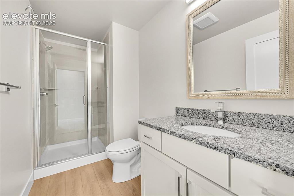 Image 27 of 35: Bathroom featuring a frameless glass shower enclosure, a white ceramic toil