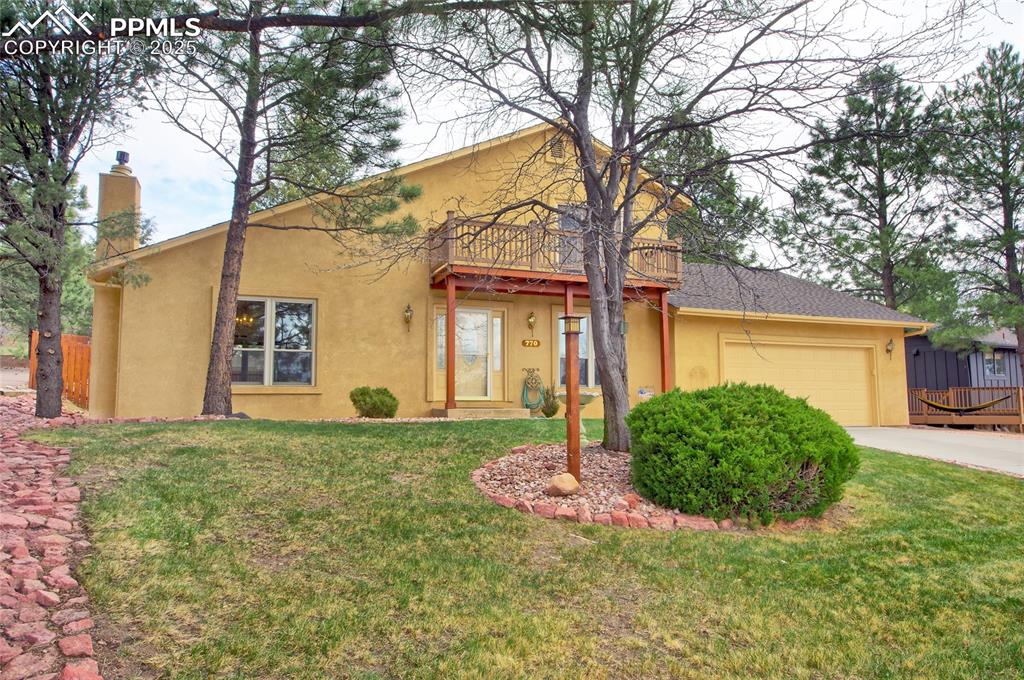Image 2 of 48: View of front of home with stucco siding, a garage, a chimney, concrete dri