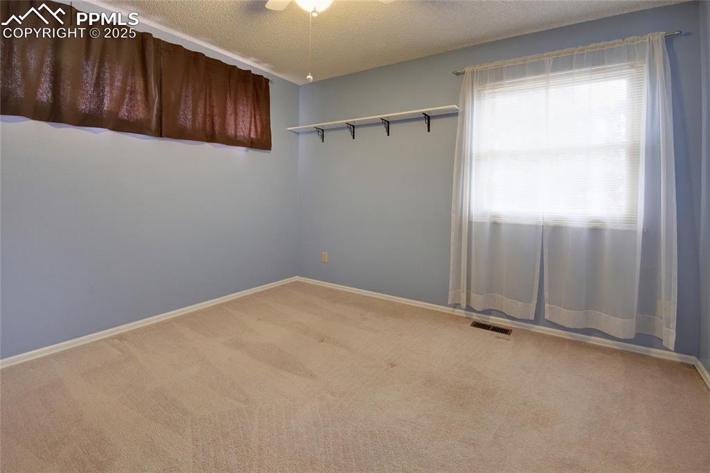 Image 22 of 48: Empty room featuring carpet flooring, a textured ceiling, and baseboards