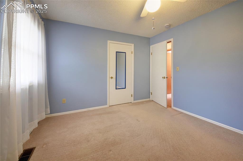 Image 23 of 48: Unfurnished room with light carpet, ceiling fan, baseboards, and a textured