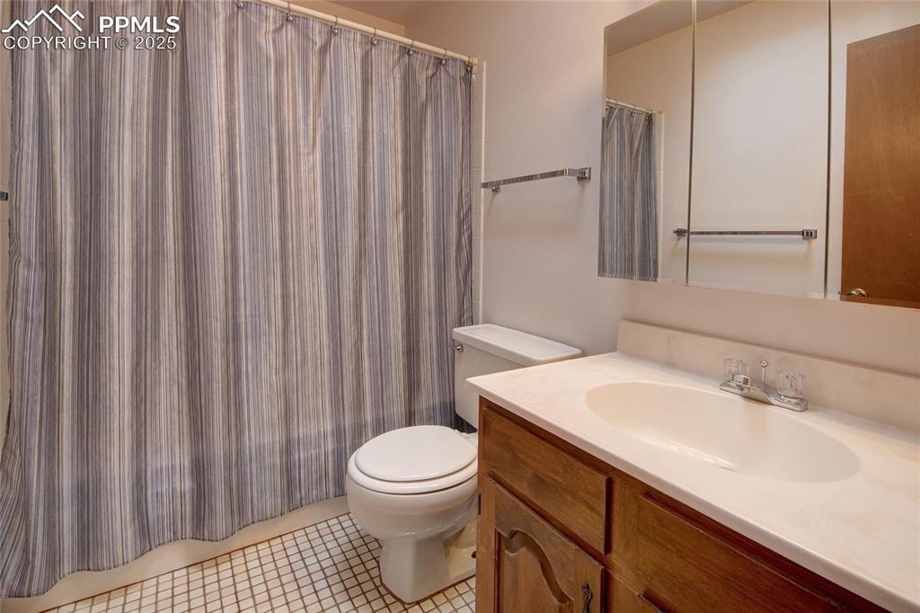 Image 26 of 48: Bathroom with toilet, vanity, and curtained shower