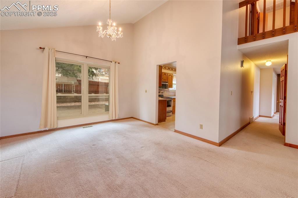 Image 8 of 48: Spare room featuring light colored carpet, a chandelier, baseboards, and hi