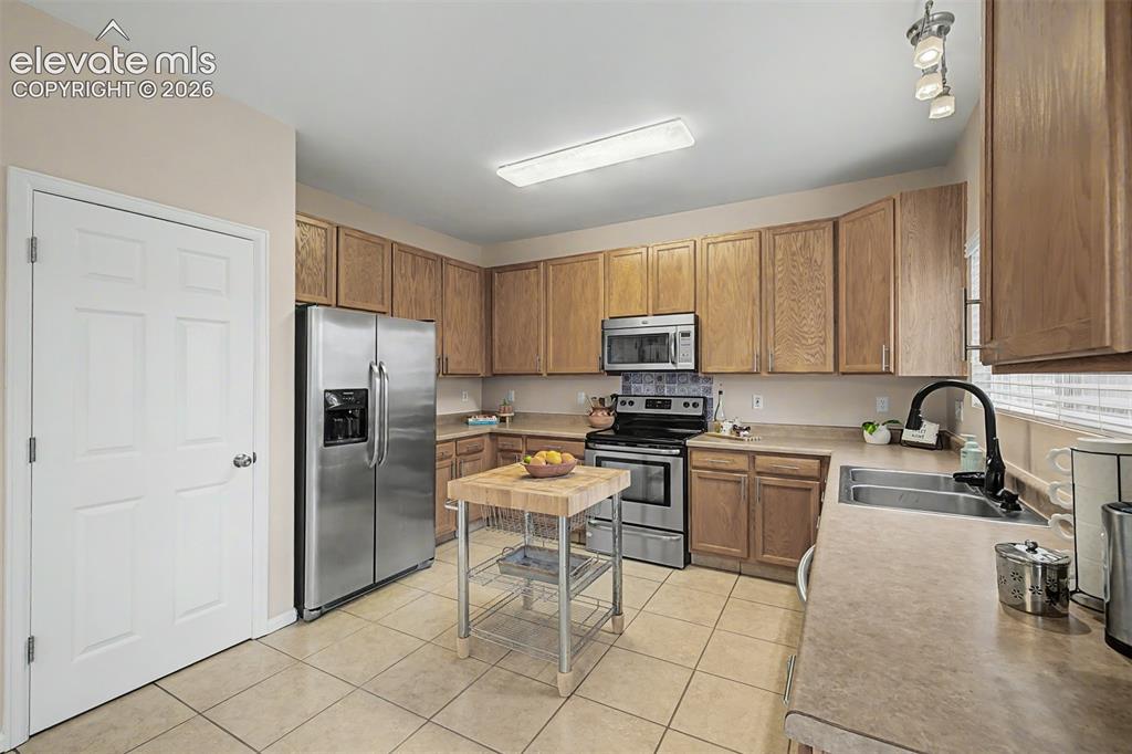 Image 14 of 45: Kitchen featuring wood cabinetry, stainless steel appliances, and ceramic t