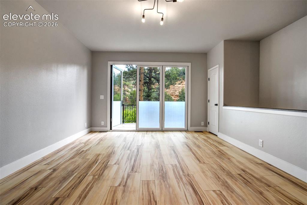 Image 10 of 48: Spacious room featuring wood-finish flooring, a contemporary ceiling light 