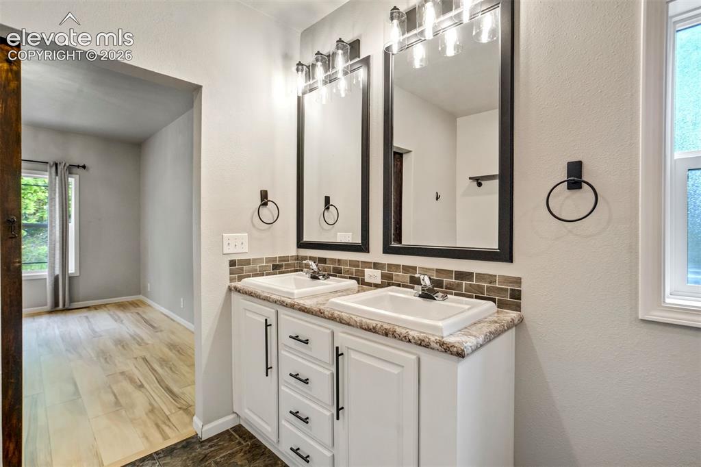 Image 19 of 48: Dual vanity featuring two undermount sinks, speckled countertops, and a mos
