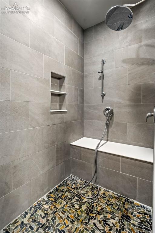 Image 21 of 48: Primary 5 piece bath Shower featuring large format gray wall tiling, a buil