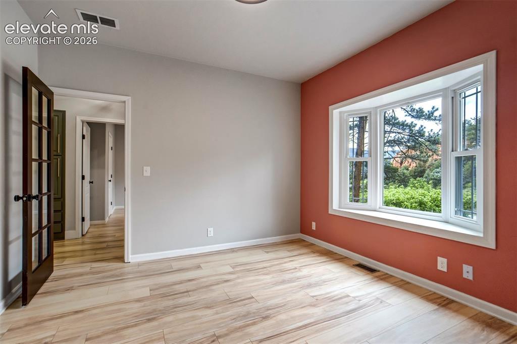Image 26 of 48: Light-toned wood-finish flooring complements a neutral wall and a contrasti