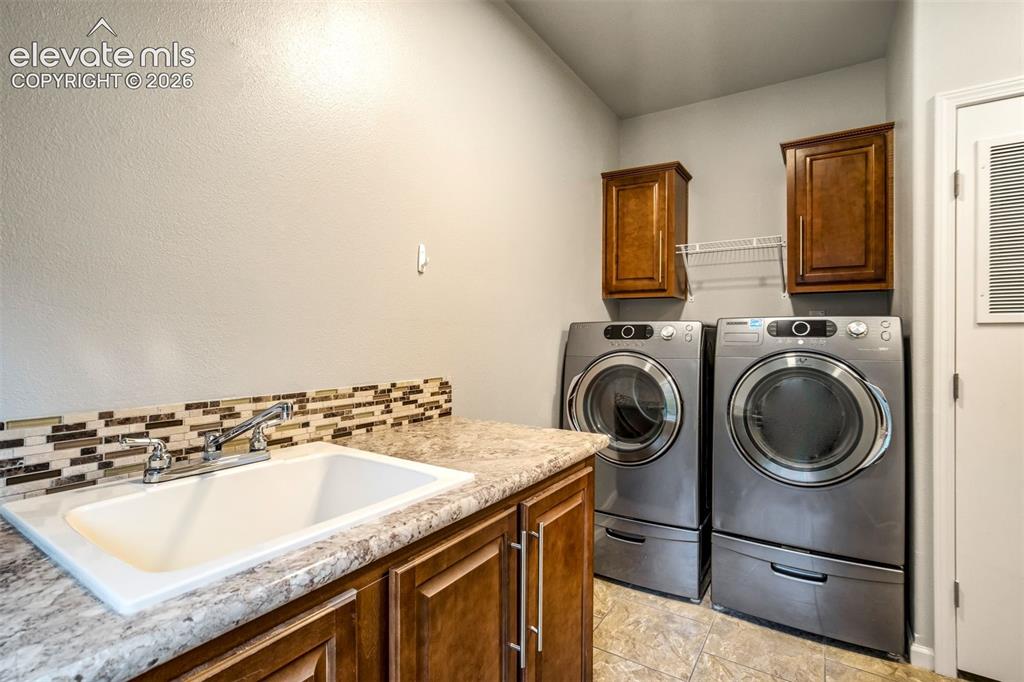 Image 30 of 48: Dedicated laundry area featuring a utility sink with chrome faucet, mosaic 