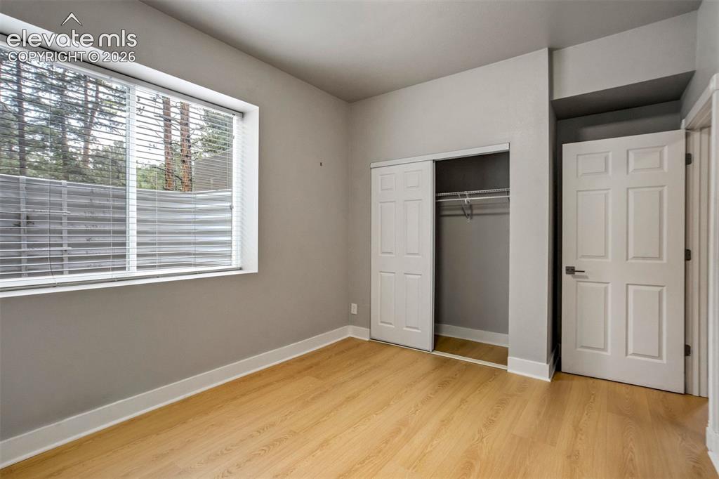 Image 38 of 48: Room featuring wood-finish flooring, a large window with blinds, a bi-fold 