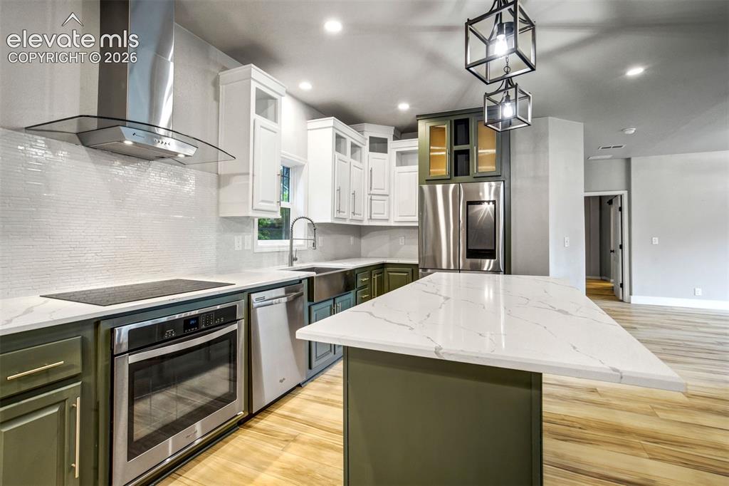 Image 4 of 48: Kitchen featuring two-tone cabinetry with white upper cabinets and sage gre