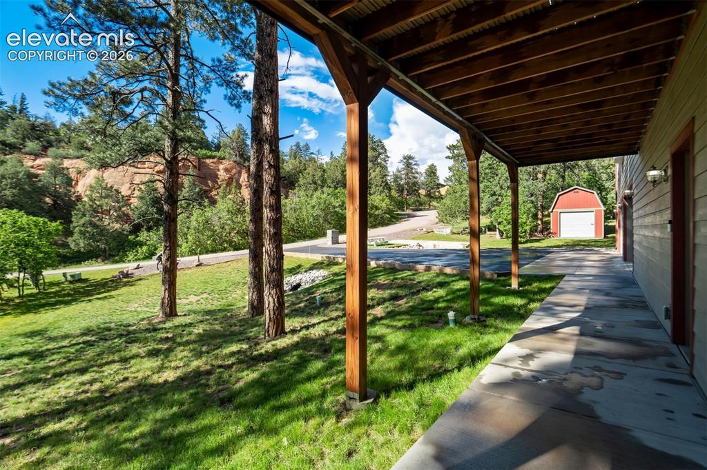 Image 42 of 48: Covered patio with exposed wood beams and posts