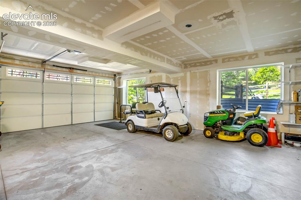 Image 45 of 48: Spacious garage featuring a large automatic overhead door with transom wind