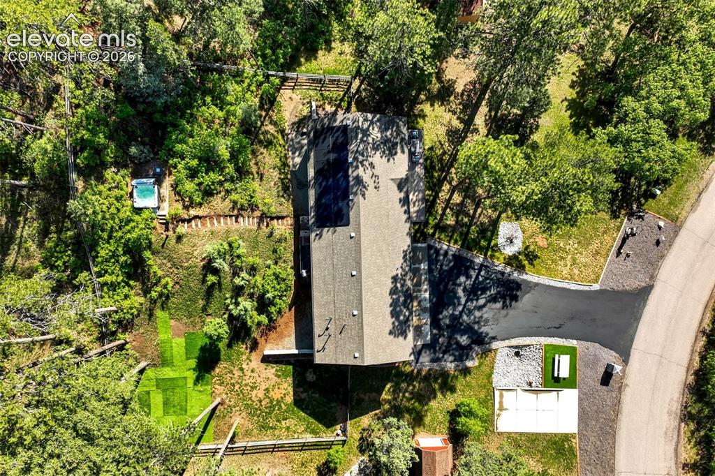 Image 47 of 48: Aerial view of the property featuring a main structure with solar panels, a