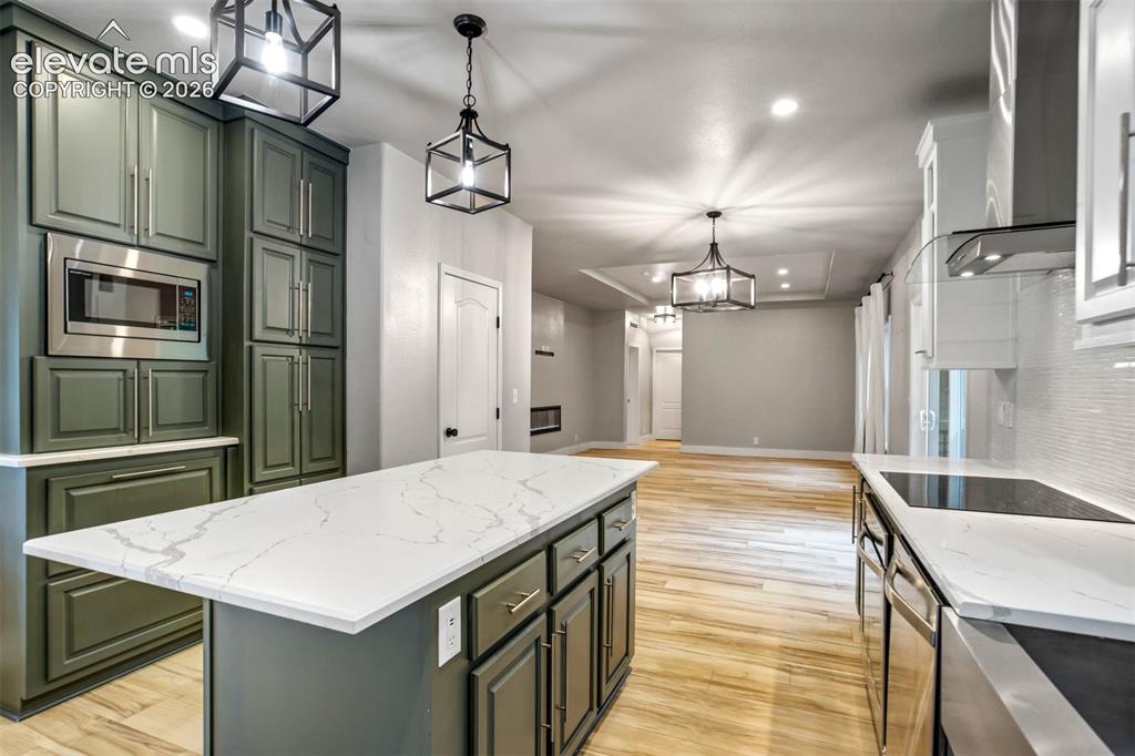 Image 6 of 48: Kitchen featuring a central island with a solid surface countertop, sage gr