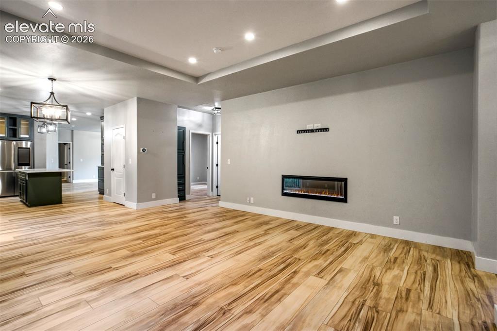 Image 8 of 48: Open concept living area featuring wood-finish flooring, a linear electric 