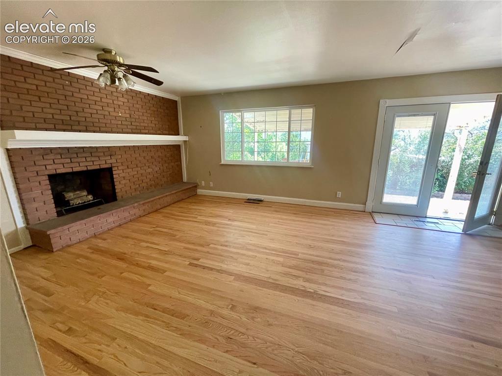 Image 8 of 37: Spacious Living Area Featuring Brick Veneer Wood Burning Fireplace with Hea