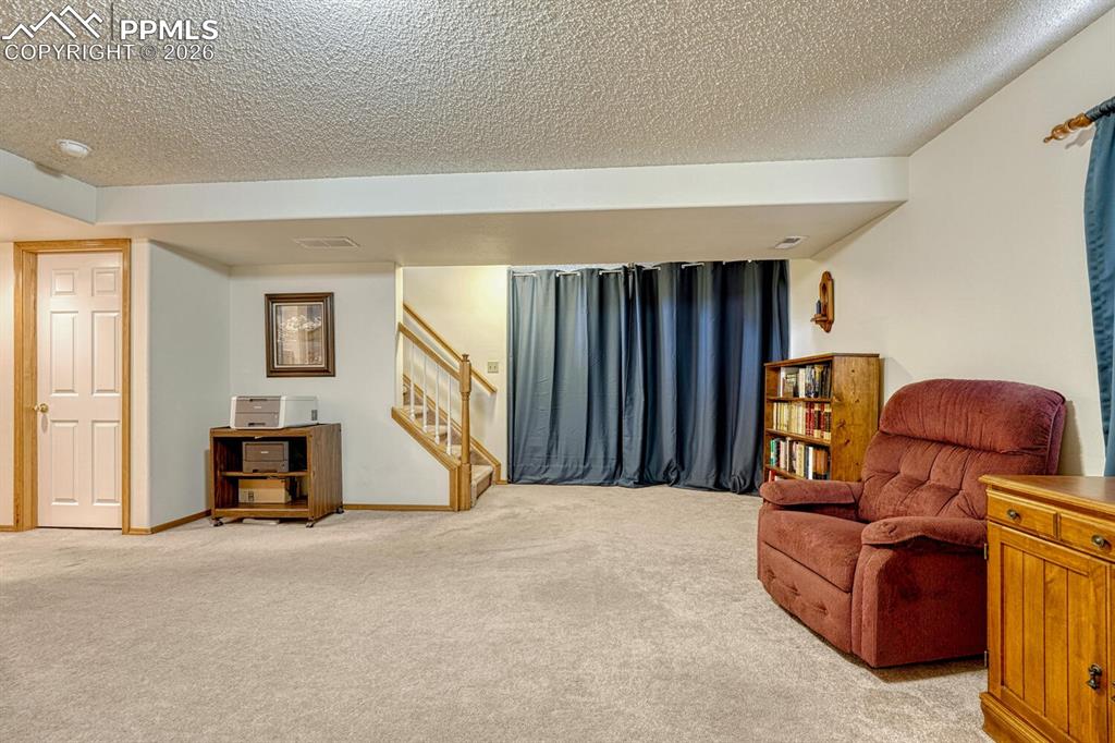 Image 27 of 36: Another view of the Family room in Basement. Behind hte blue curtain is a