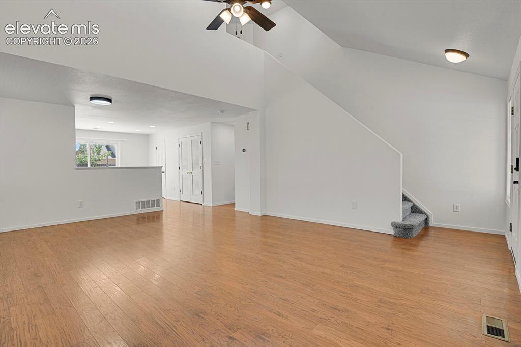 Image 11 of 49: Living area featuring wood-finish flooring, vaulted ceilings, and a ceiling