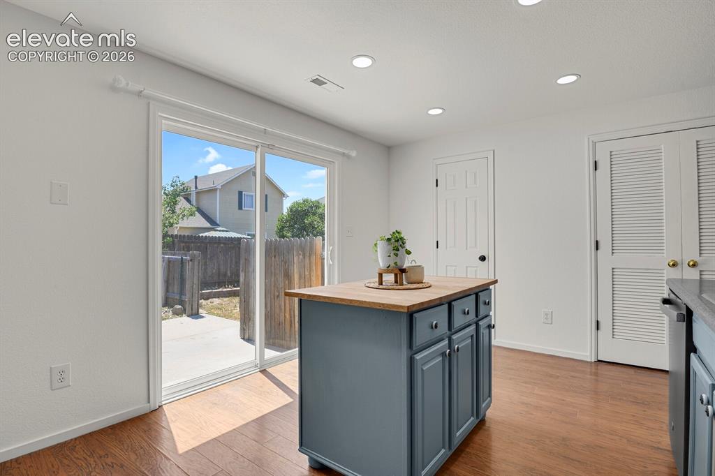 Image 16 of 49: Kitchen featuring a central island with wood-finish countertop, recessed li