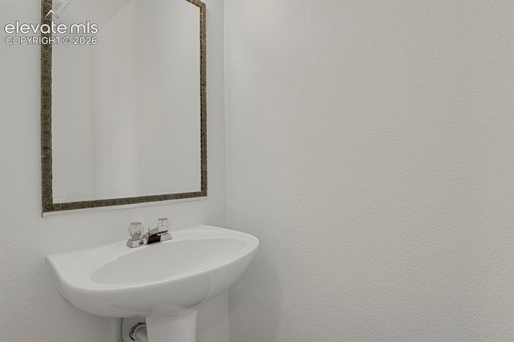 Image 19 of 49: Pedestal sink with chrome faucet, framed mirror, and textured wall finish