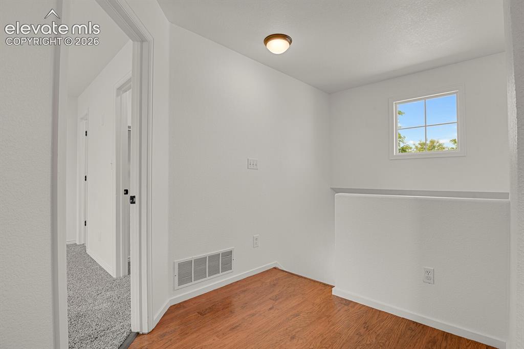 Image 22 of 49: Bright hallway with wood-finish flooring, a contemporary ceiling light fixt