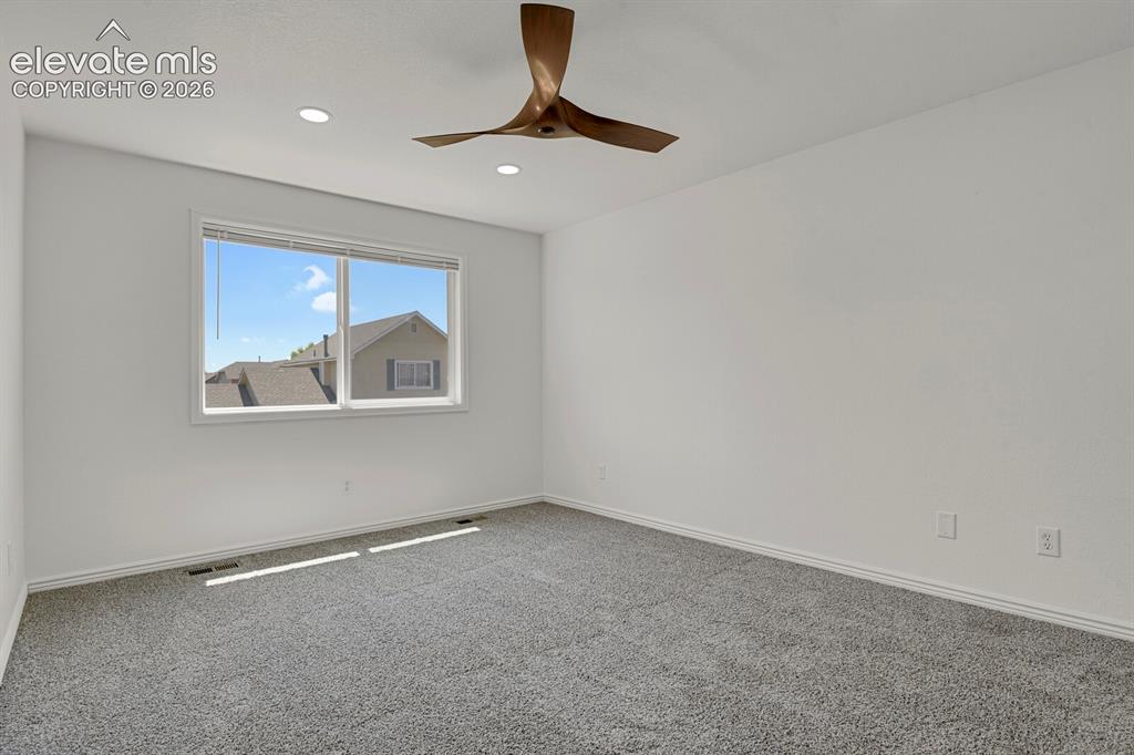 Image 23 of 49: Spacious room featuring clean white walls, grey textured carpeting, and a l