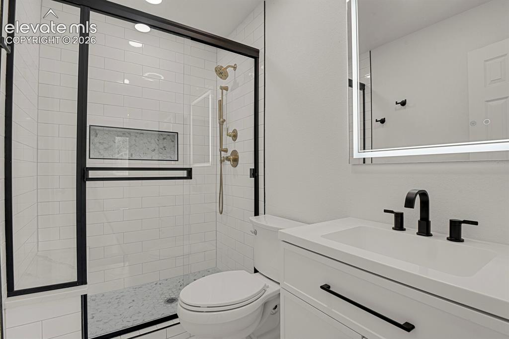 Image 27 of 49: Contemporary bathroom featuring a walk-in shower with black-framed glass en