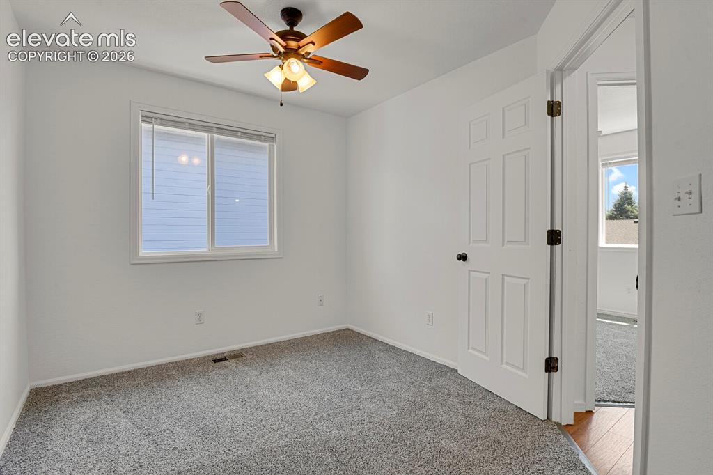 Image 29 of 49: Room featuring a neutral color palette, wood-look ceiling fan, window with